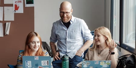 Mannlig lærer sammen med to elever i klasserom, videregående skole.