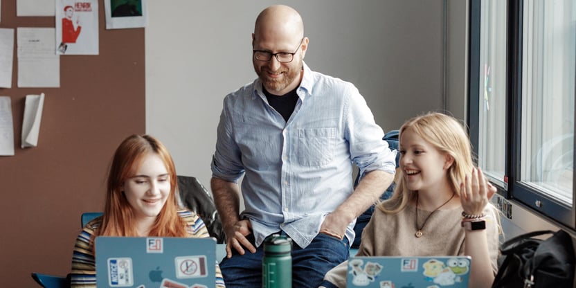 Mannlig lærer sammen med to elever i klasserom, videregående skole.