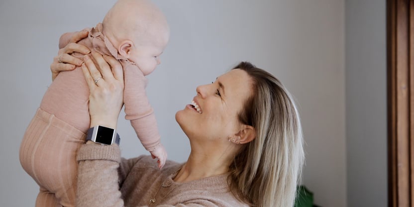Mor som smiler og løfter baby