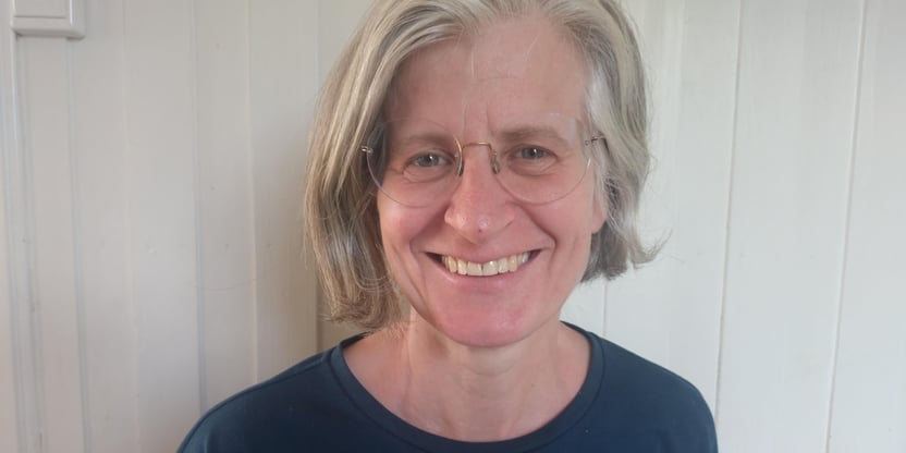 Nærbilde av Elin Tandberg, hun smiler, har briller og halvlangt hår.