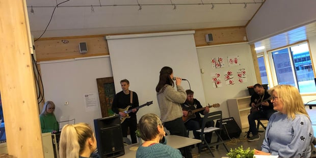 Bilde av et band som spiller med publikum i forkant.