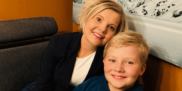 12 år gamle Leander Larsen Berg sammen med moren Kikki Berg sitter i en sofa og smiler til fotografen.