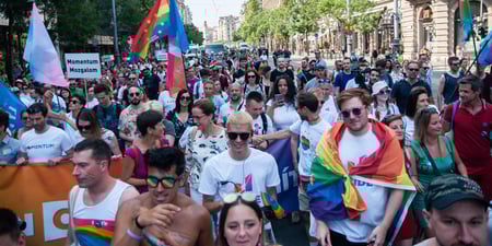 Pride-parade i Budapest med regnbueflagg og glade mennesker som går i tog