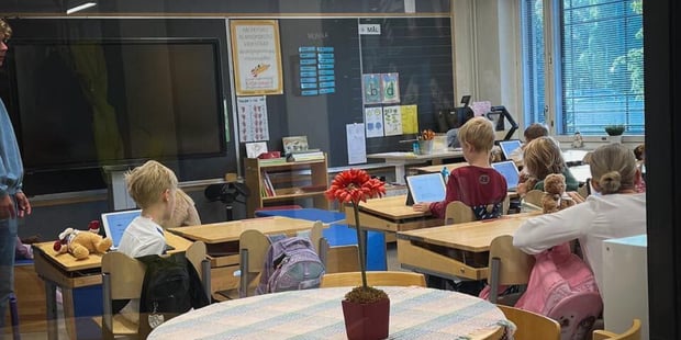 Bilde tatt utenfra og inn gjennom et vindu til et finsk klasserom. Vi ser bakhodet på elever som jobber med en oppgave. 