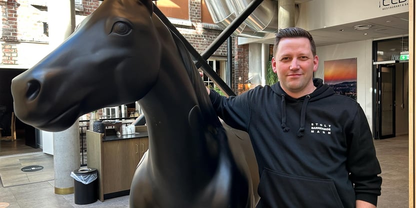 portrettbilde av en mann som står ved en hestestatue