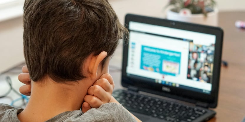 Foto av en gutt som sitter foran en laptop