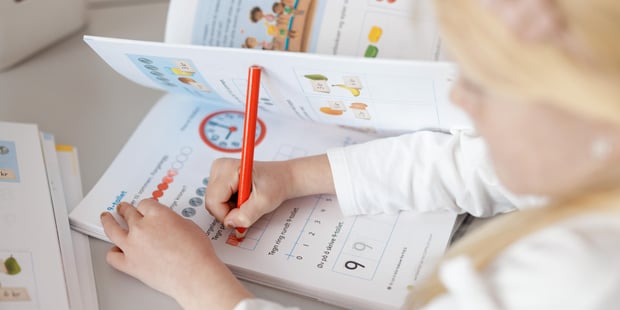 Bildet viser en elever ved Oksenøya barneskole. Hun skriver i en mattebok.
