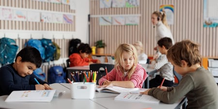 Klasserom med elever og lærer i bakgrunnen.