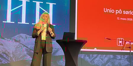 Kvinne avbildet i helfigur på podiet med mikrofon