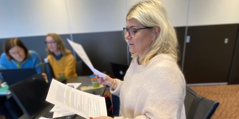 Kvinne som leser fra et dokument. avbildet i halvfigur
