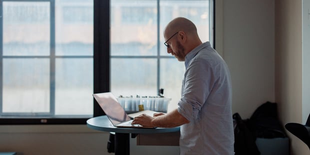 Mannlig lærer står og leser i PC, Klasserom, Videregående skole