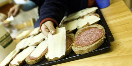 Bilde av et fat med brødskiver og en hånd som tar en skive med pålegg