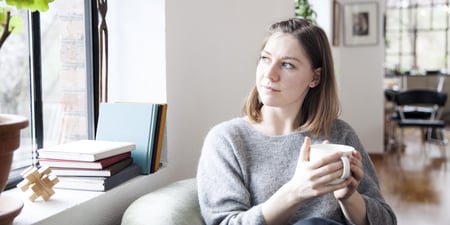 Jente som sitter i en stol og ser ut av vinduet