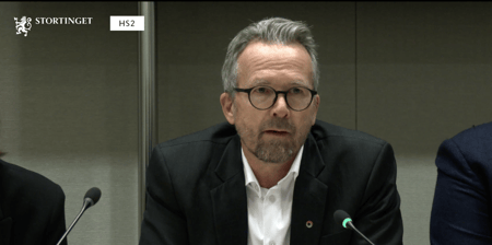 Skjermdump av leder i Utdanningsforbundet, Geir Røsvoll - hvit mann med hvit skjorte og dressjakke, og briller, som snakker inn i en mikrofon