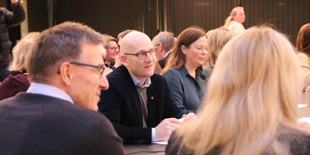 Mennesker sitter rundt et bord og snakker.