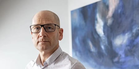 Nærbilde av Steffen Handal foran et blått maleri.