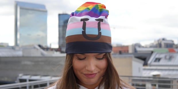 Ung dame som har på seg Pride-lue i 11 farger. Urban bakgrunn.