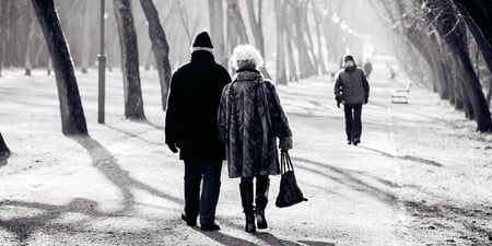 En dame og en mann går tur langs en vei. Svart-hvitt-bilde.