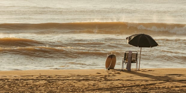 Foto av en strand, hav, strandparasoll og strandstol