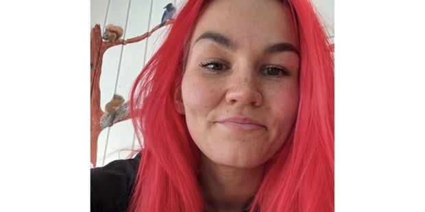 En kvinne poserer med sterkt rødt farget hår