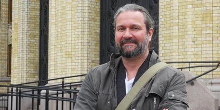 Thomas Nordgård står foran Stortinget. Han har armene i kors og smiler, men er også bestemt.