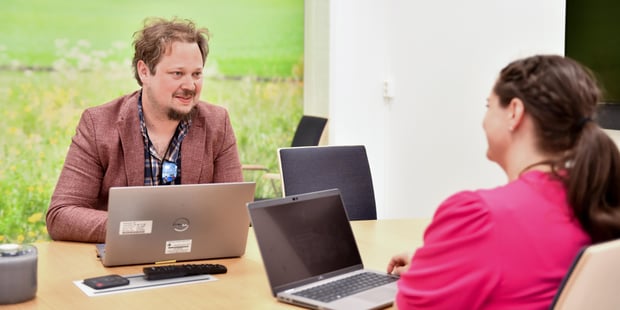To personer, dame og mann, sitter på møterom og planlegger