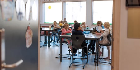 Bildet viser elever ved Oksenøya barneskole, 1. og 6. klasse i 2024. Disse små barna sitter i klasserommet og spiser nistepakken sin.
