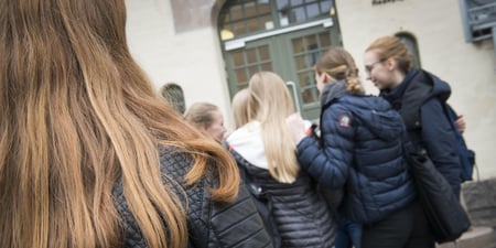 En gjeng med jenter står tett sammen i en skolegård.