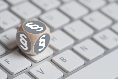 Terning med paragraftegn på alle sider, liggende oppå et tastatur