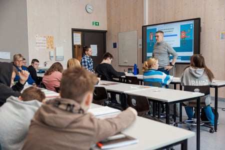 Klasserom med flere elever og 3 lærere, En lærer står foran tavle og sier noe. Foto