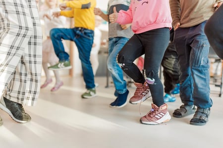 Bildet viser elever ved en barneskole som beveger seg i klasserommet, det ser ut som høye kneløft. Vi sr bare elevene fra livet og ned.
