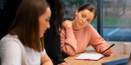 Foto av to studenter og en kvinne som diskuterer ved en pult
