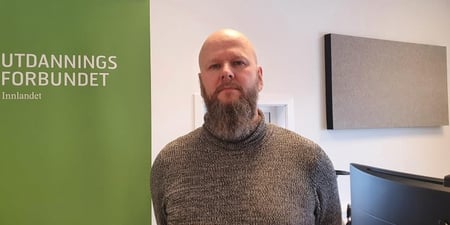 Bilde av Thore Johan Nærbøe stående på kontoret ved siden av en roll-up med påskriften Utdanningsforbundet Innlandet