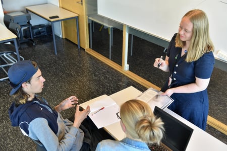 Kvinnelig lærer holder fram kaffe foran elev. Foto.