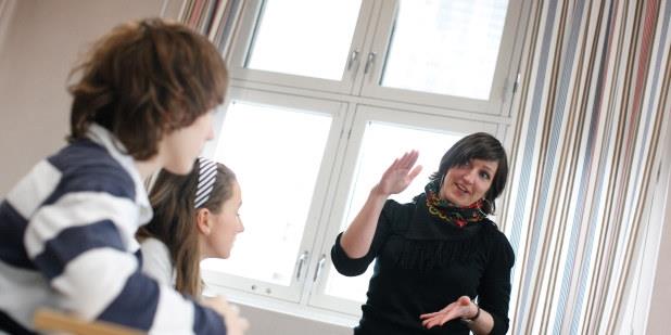 Lærer diskuterer med to elever. Foto.