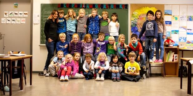 Et klassebilde av 1 lærer og 22 elever. Foto.