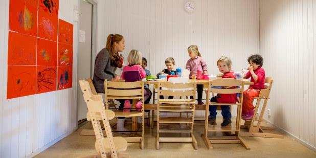Barnehagebarn som sitter rundt et bord og spiser. Foto.