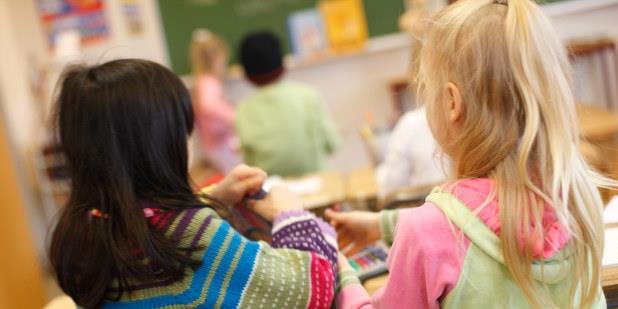 To jenter samarbeider ved skolepulten. Foto