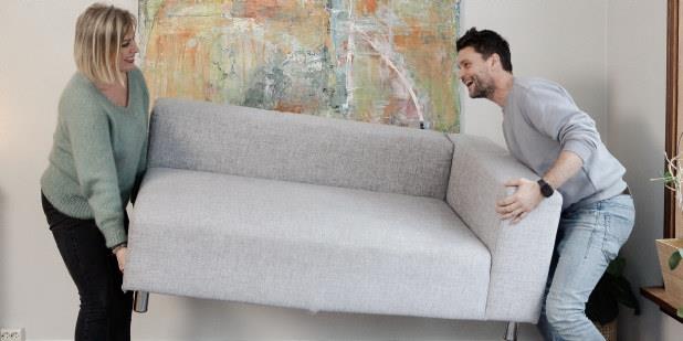 Par som løfter sofa. Foto