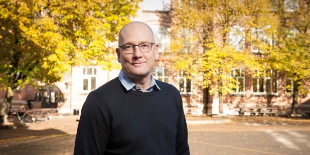 Foto av Steffen Handal som smiler i en skolegård