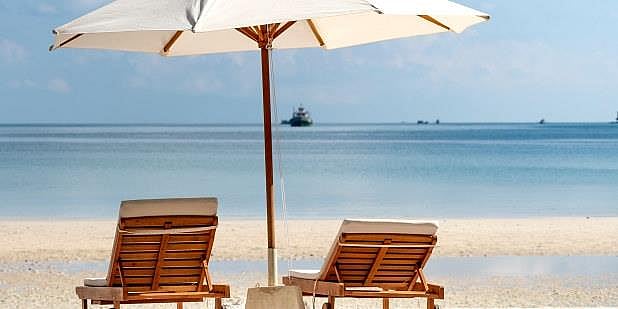 To strandstoler under parasoll på stranden.