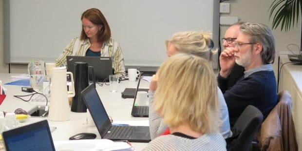 Vi ser bilde av personer som sitter rundt et bord på kurs. 