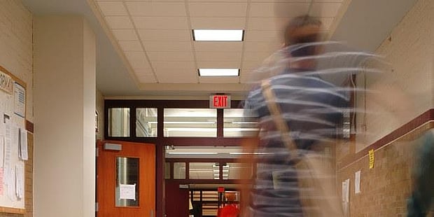 Foto av elev som er uskarp  og med bevegelse i bilde som går alene i en skolekorridor. Illustrasjonsfoto