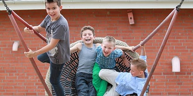 glade gutter som leker i en huske. illustrasjonsfoto