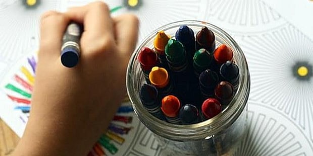 Illustrasjonsfoto av barnehånd som tegner med fargestifter