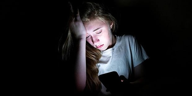 fortvilet ung jente med mobiltelefon i mørket
