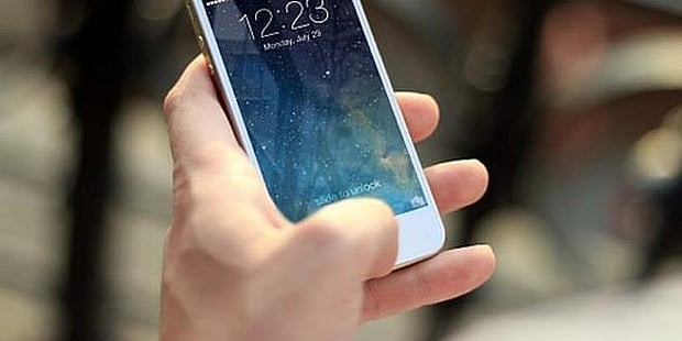 Bilde av en hånd som holder en iphone. Illustrasjonsfoto