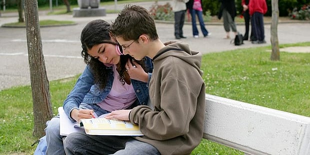 skoleelever, en jente og en gutt, som ser i en bok sammen