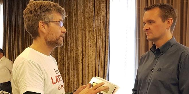Vi ser bilde av HTV Eskil Berggren i halvfigur med kalkulator i hånda i samtale med regiondirektør i KS Agder, Steiner Eilertsen.