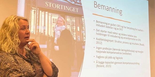 Vi ser bilde av en kvinne som holder foredrag. Hun er avbildet i halvfigur